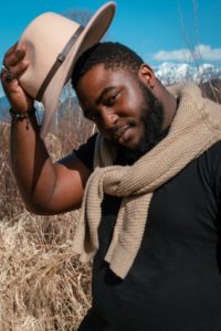 hat band man tipping hat with hatband and sweater draped over his neck